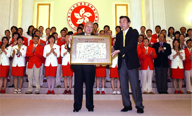  国 家 体 育 总 局 局 长 袁 伟 民 把 国 家 奥 运 金 牌 运 动 员 的 签 名 卡 赠 送 给 行 政 长 官 。