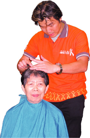 A volunteer hair stylist gives this elderly woman a nice neat trim.