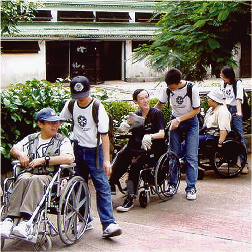 Young volunteers help the disabled enjoy some sunshine.